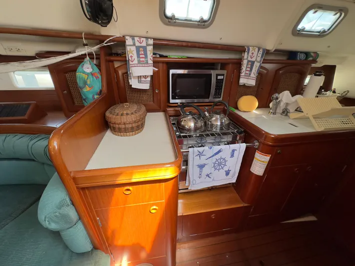  Yacht Photos Pics Cozy kitchen area in a 2000 Beneteau 411 sailboat with wooden cabinetry and appliances.