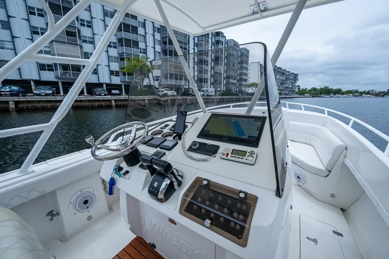  Yacht Photos Pics 2003 Intrepid 323 boat cockpit with steering wheel, navigation system, and waterfront view.