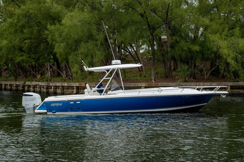  Yacht Photos Pics 2003 Intrepid 323 boat on calm water, surrounded by lush greenery.