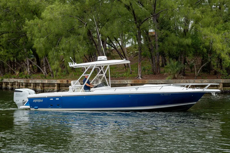  Yacht Photos Pics 2003 Intrepid 323 boat cruising on a calm waterway, surrounded by lush greenery.
