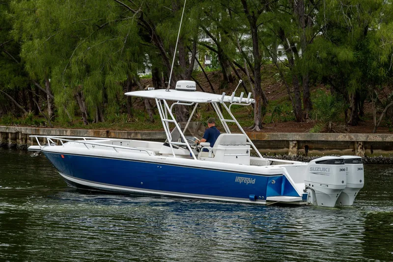  Yacht Photos Pics 2003 Intrepid 323 boat with dual Suzuki engines cruising near a wooded shoreline.