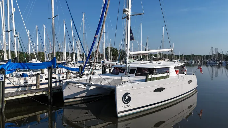 Sirena Yacht Photos Pics 2015 Fountaine Pajot Helia 44 catamaran docked in a marina, surrounded by sailboats.