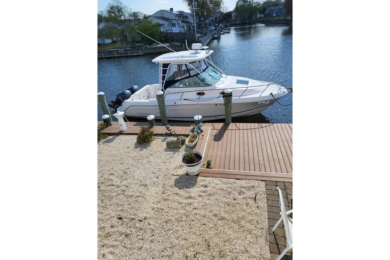  Yacht Photos Pics 2015 Robalo R305 Walkaround boat docked by a waterfront home.