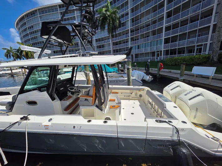 Grey Hawk Yacht Photos Pics 2023 Boston Whaler 360 Outrage docked near modern waterfront building.