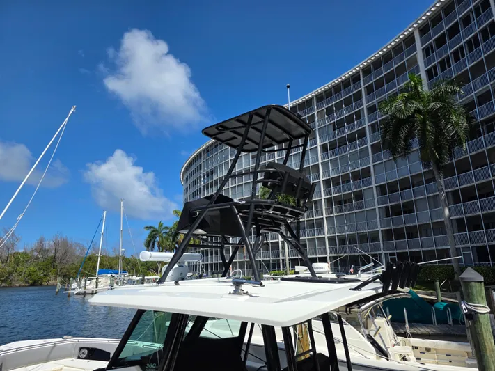Grey Hawk Yacht Photos Pics 2023 Boston Whaler 360 Outrage boat docked near modern building and palm trees.