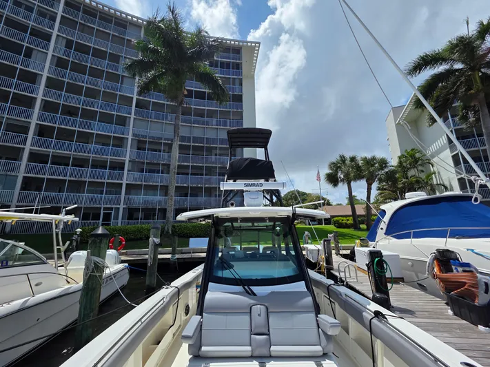 Grey Hawk Yacht Photos Pics 2023 Boston Whaler 360 Outrage docked near modern waterfront buildings.