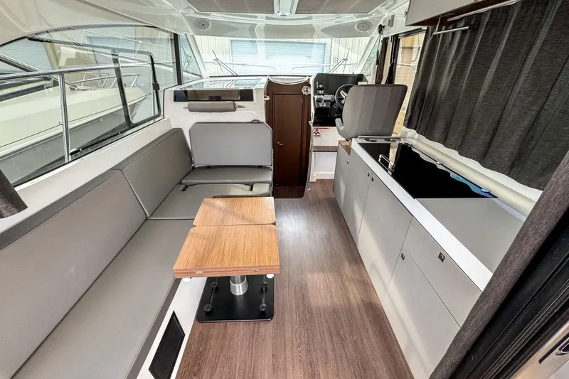  Yacht Photos Pics 2024 Beneteau Antares 11 interior with modern seating, wooden table, and sleek kitchen area.