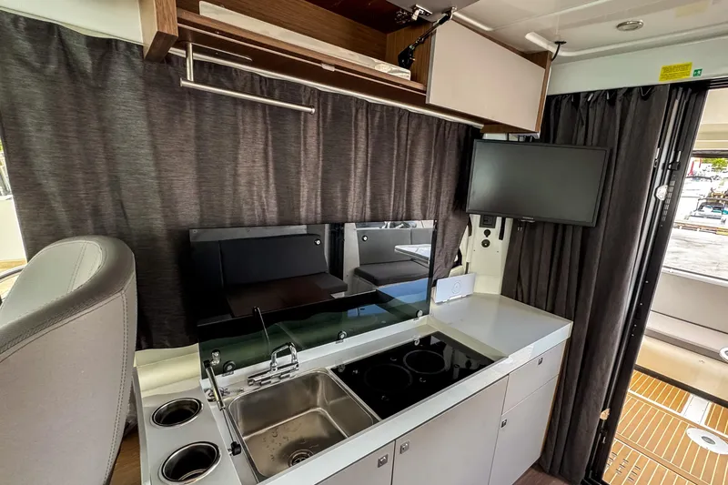  Yacht Photos Pics 2024 Beneteau Antares 11 interior kitchen with sink, stove, and mounted TV.