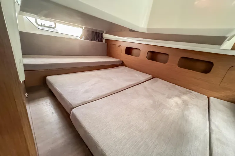 Yacht Photos Pics 2024 Beneteau Antares 11 cabin interior with cozy bedding and wooden accents.