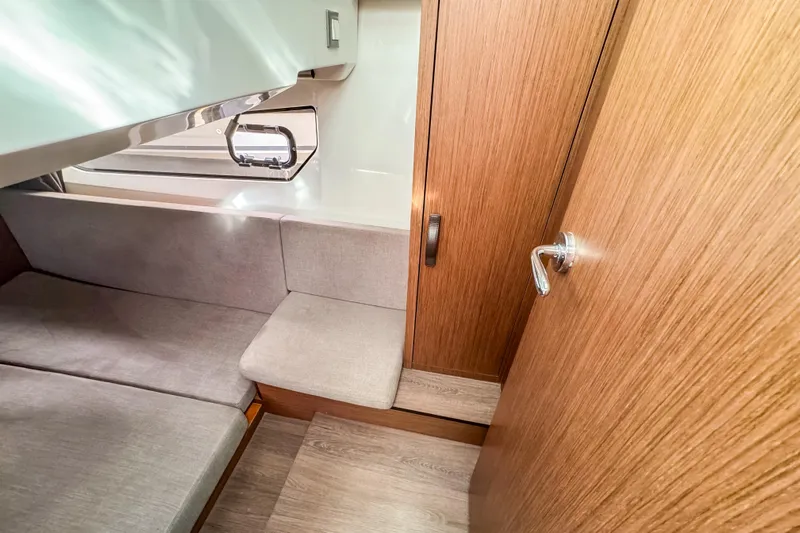  Yacht Photos Pics 2024 Beneteau Antares 11 cabin interior with wood finish and seating area.