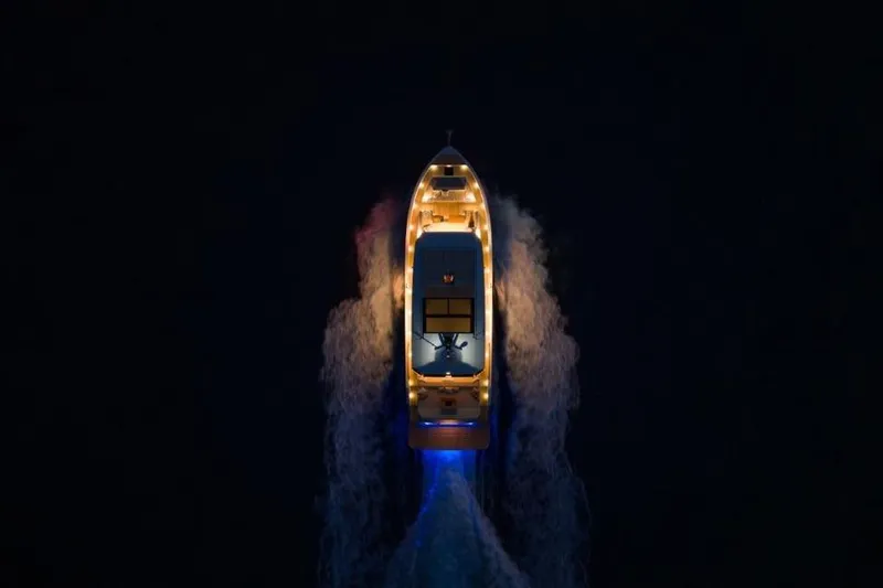  Yacht Photos Pics Aerial view of 2025 De Antonio Yachts D60 illuminated at night, cruising through dark waters.
