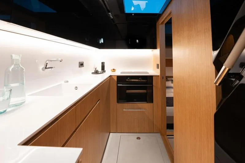  Yacht Photos Pics Modern kitchen interior of 2025 De Antonio Yachts D60, featuring sleek wood cabinetry and minimalist design.
