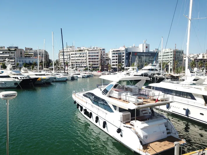 Goldinia Yacht Photos Pics Luxury 2021 Azimut 72 yacht docked in a marina, surrounded by other boats and cityscape.