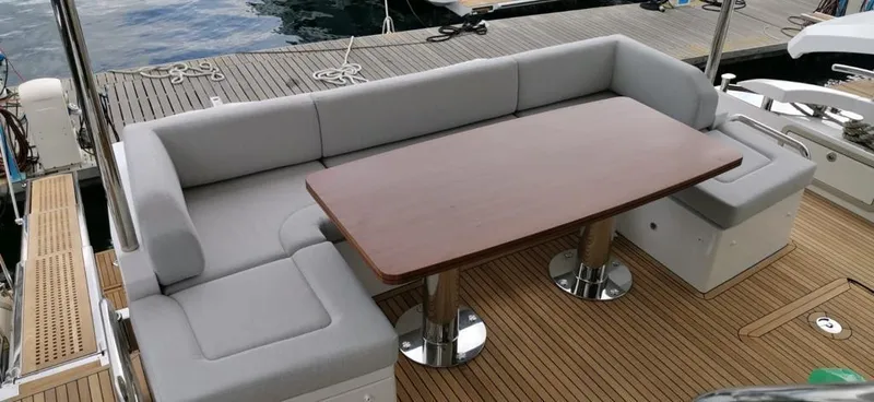 Goldinia Yacht Photos Pics Luxurious seating area on 2021 Azimut 72 yacht with wooden table and gray cushions.