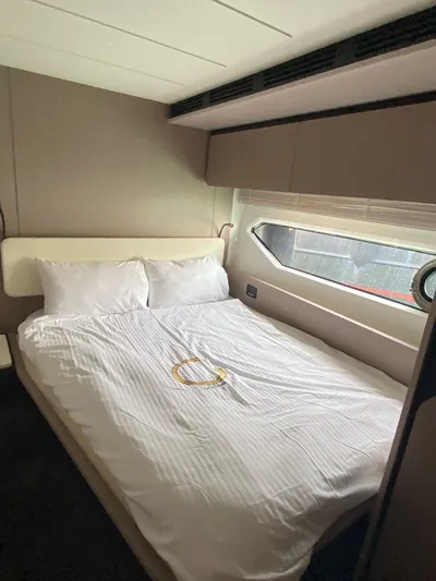 Goldinia Yacht Photos Pics Luxurious bedroom interior of a 2021 Azimut 72 yacht with a large bed and window.