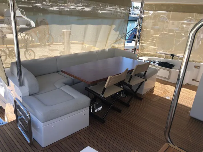 Goldinia Yacht Photos Pics Luxurious seating area on a 2021 Azimut 72 yacht with wooden table and chairs.