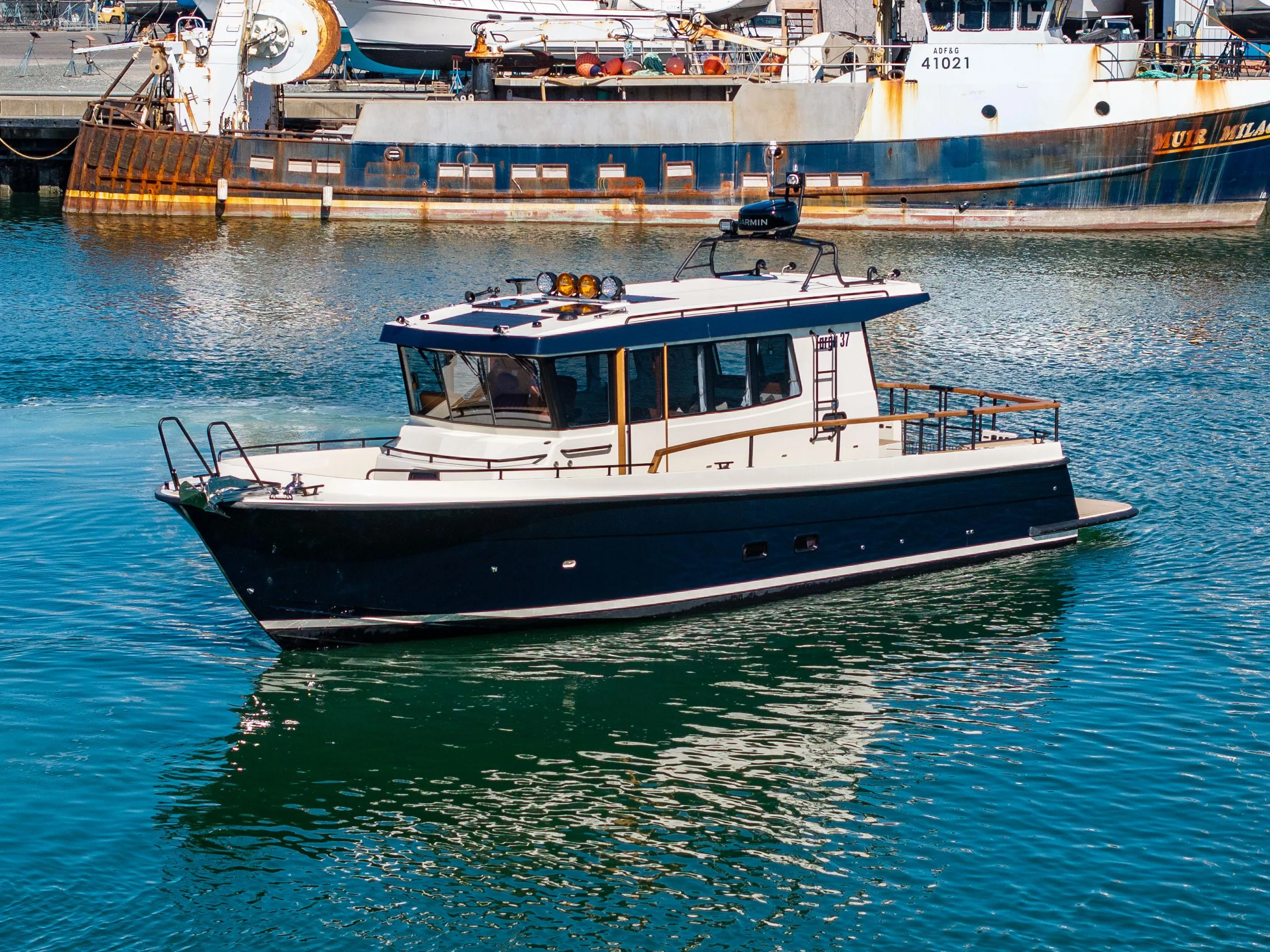 2025 Targa 37 boat cruising in a harbor with industrial background.