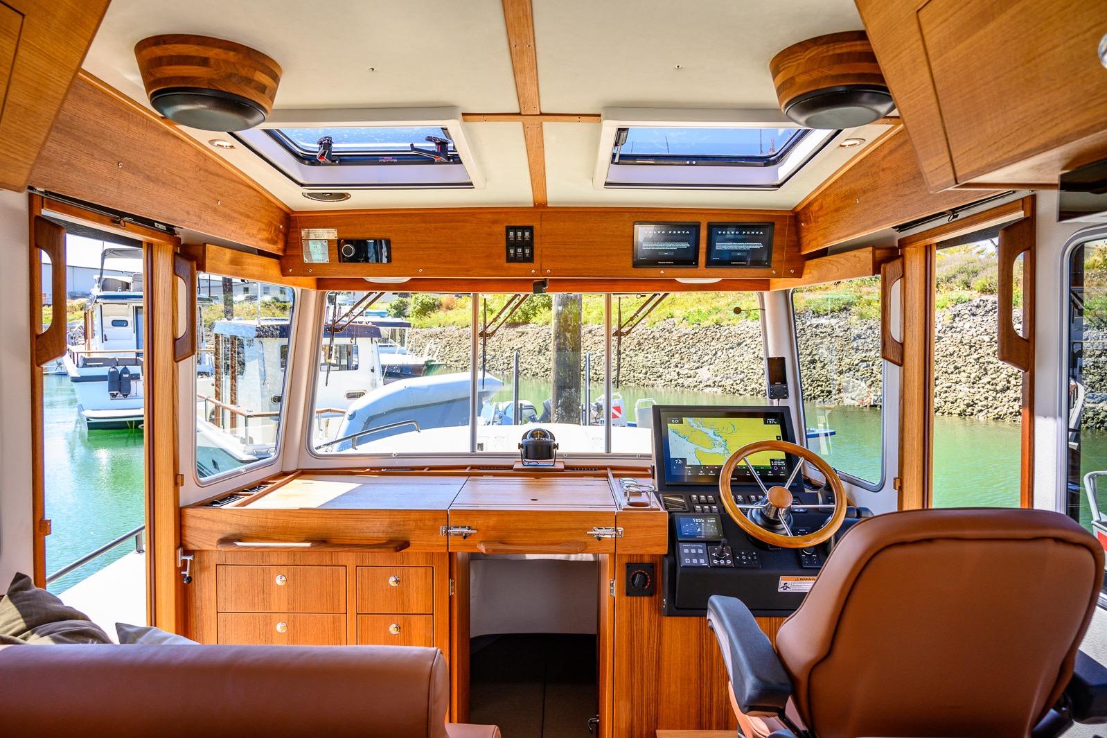 Interior of 2025 Targa 37 boat, featuring wooden helm, navigation screens, and marina view.