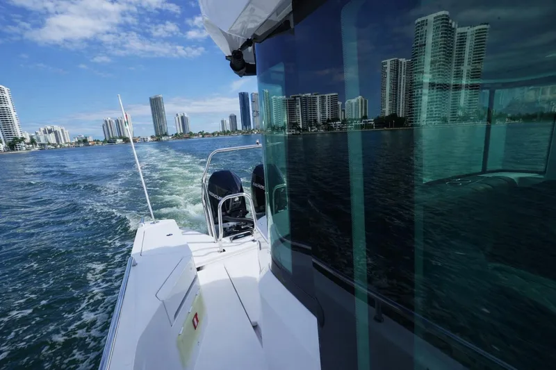  Yacht Photos Pics 2022 Axopar 37 XC Cross Cabin cruising near city skyline on a sunny day.