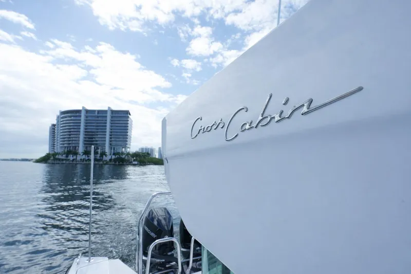  Yacht Photos Pics 2022 Axopar 37 XC Cross Cabin boat near waterfront buildings under cloudy sky.