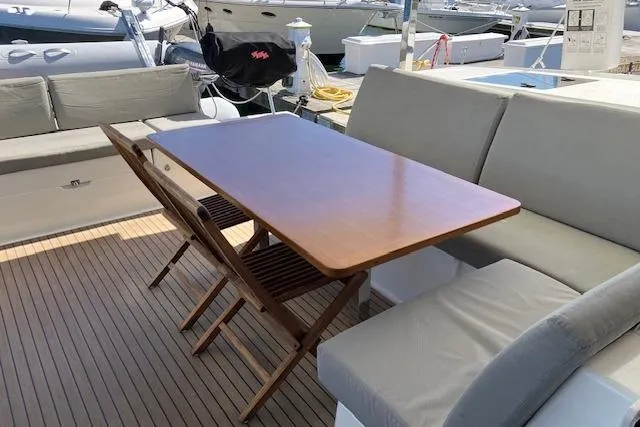 Paire De Jacques Yacht Photos Pics Outdoor seating area on 2021 Fountaine Pajot Isla 40 catamaran with wooden table and cushioned benches.