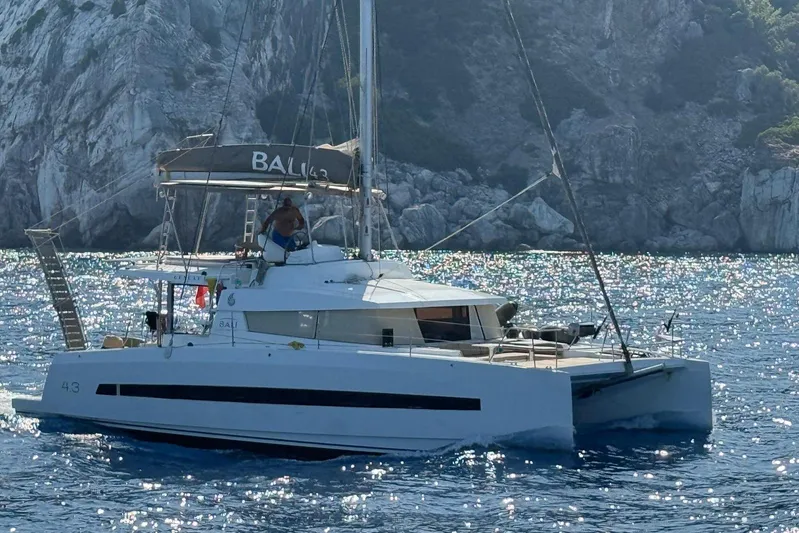  Yacht Photos Pics 2017 Bali 4.3 catamaran sailing near rocky coastline in sparkling blue waters.