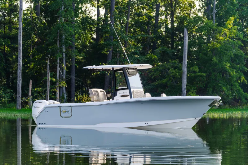  Yacht Photos Pics 2026 Sea Hunt Gamefish 25 boat on calm water, surrounded by lush trees.