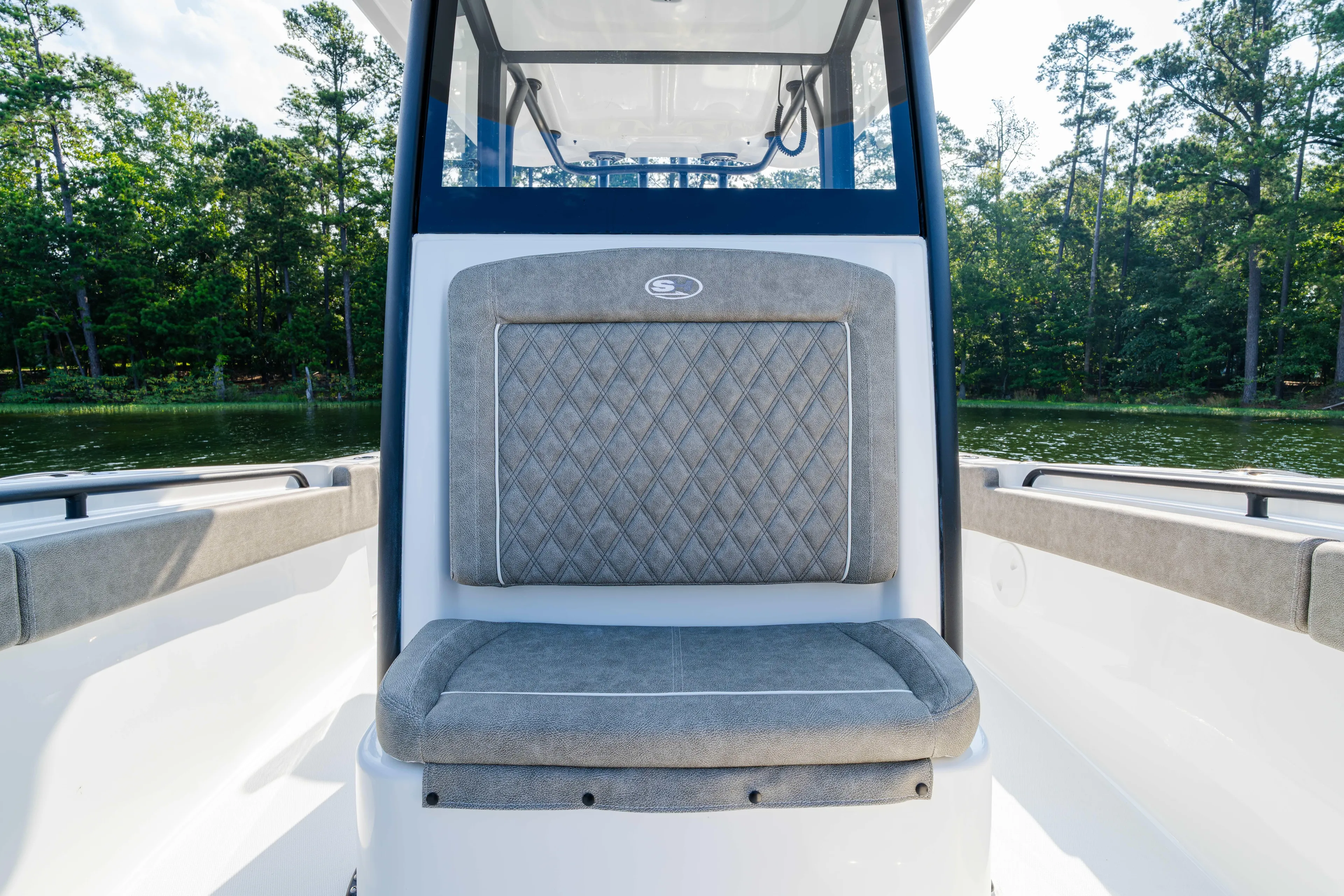  Yacht Photos Pics 2026 Sea Hunt Gamefish 25 boat interior with cushioned seating, surrounded by lush greenery.