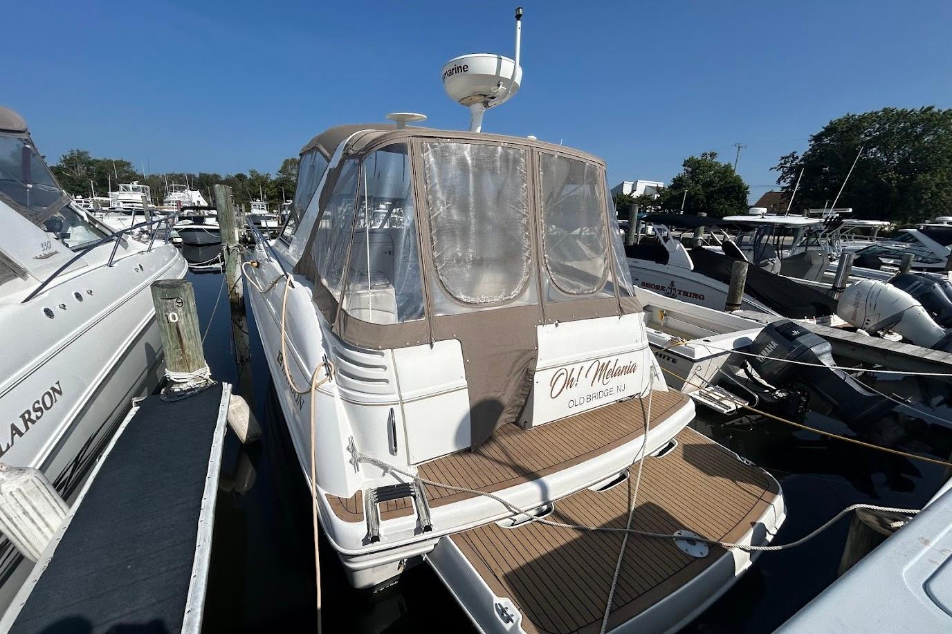 2001 Larson Cabrio 330 boat docked at marina under clear blue sky.