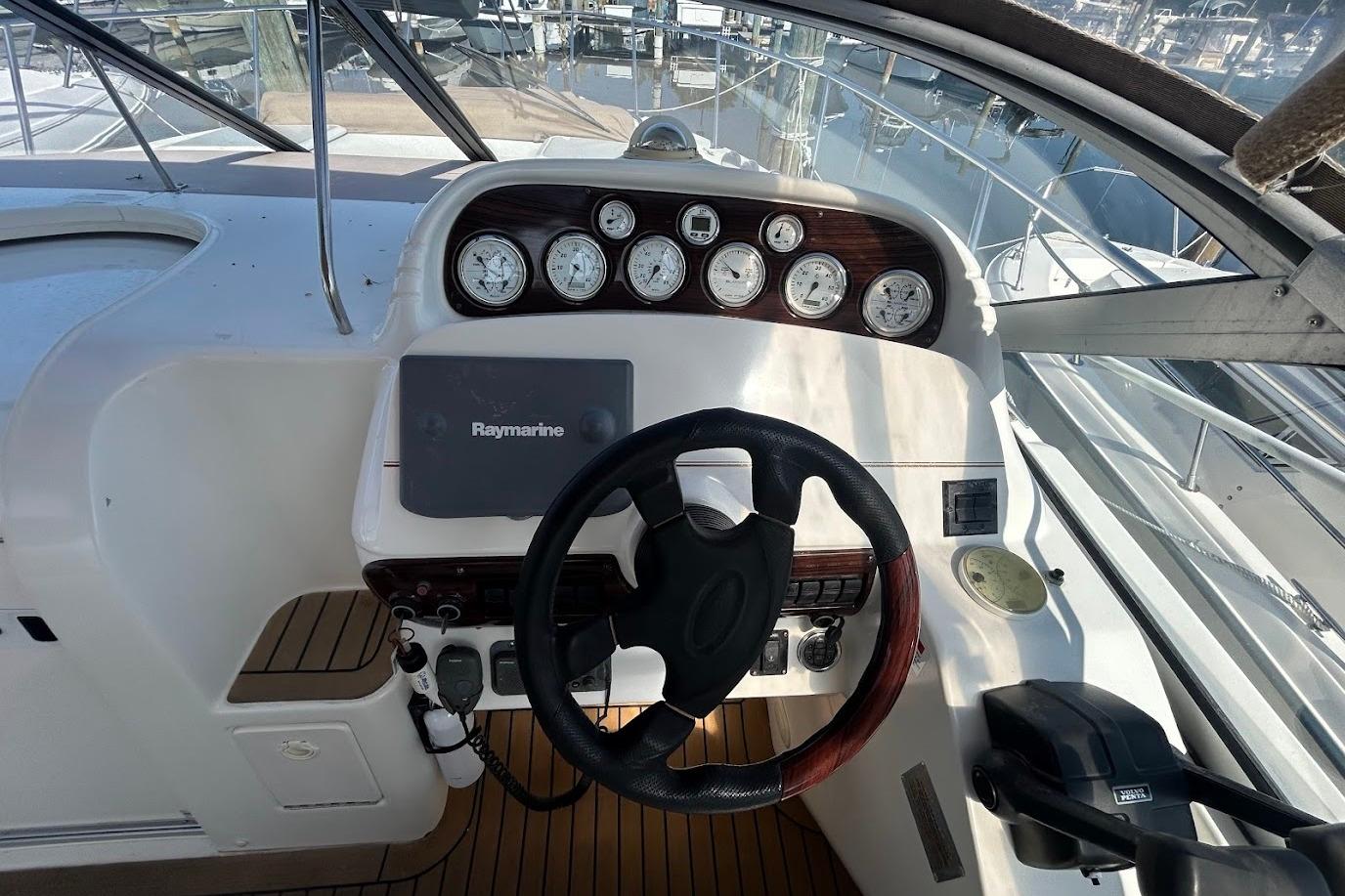 2001 Larson Cabrio 330 helm with Raymarine navigation, gauges, and steering wheel.