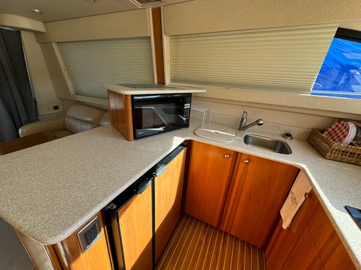 Baby Cake Yacht Photos Pics 2004 Meridian 381 Sedan yacht interior with kitchenette, featuring microwave, sink, and wooden cabinetry.