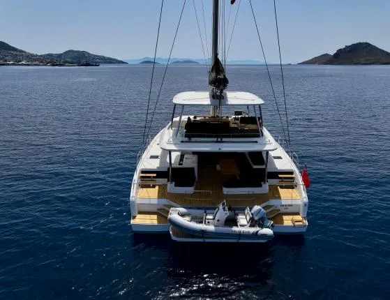  Yacht Photos Pics 2023 Lagoon 55 yacht on calm sea with scenic island backdrop.