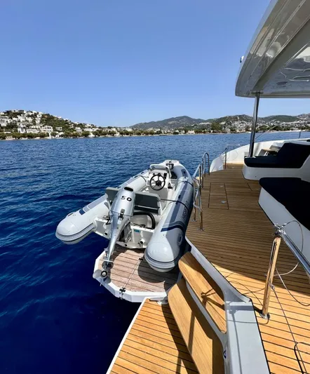  Yacht Photos Pics 2023 Lagoon 55 yacht with inflatable boat on deck, overlooking serene blue waters.