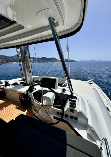  Yacht Photos Pics Cockpit view of 2023 Lagoon 55 yacht sailing on a clear blue sea.