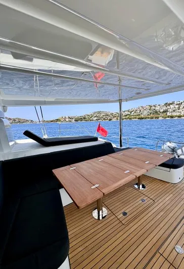  Yacht Photos Pics 2023 Lagoon 55 yacht deck with wooden table, overlooking serene blue waters.