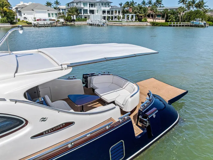 A. Noochette Yacht Photos Pics Luxurious 2024 Zeelander Z5 yacht with elegant seating, docked by waterfront homes.