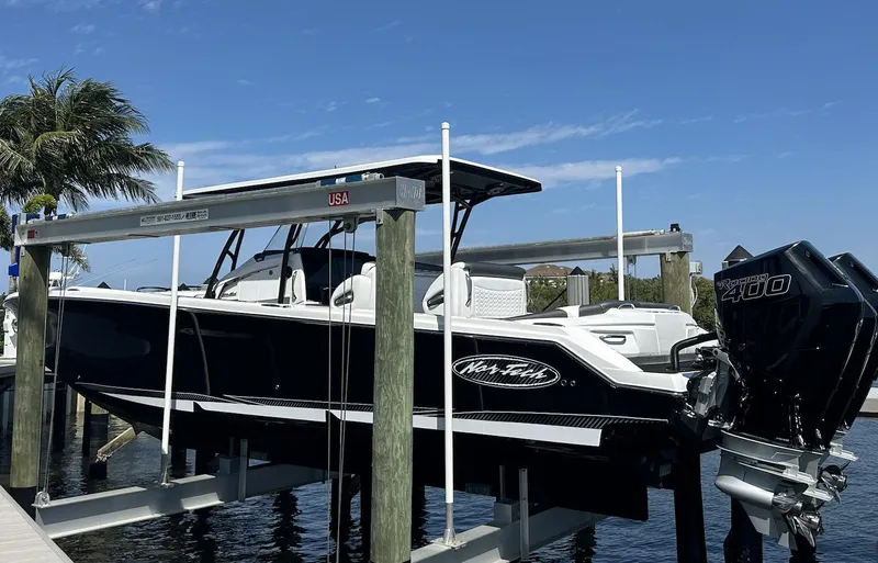  Yacht Photos Pics 2023 Nor-Tech 390 Sport Center Console boat on lift, docked by palm trees.