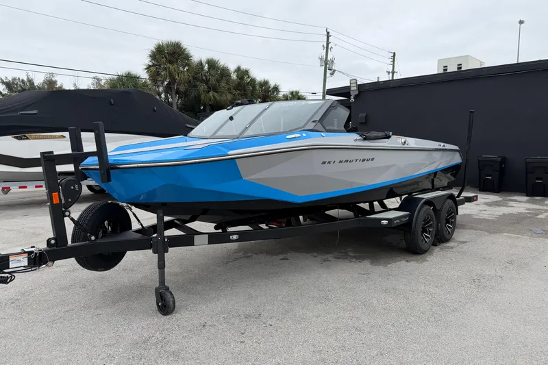  Yacht Photos Pics 2026 Nautique Ski Nautique boat in blue and gray on a trailer, parked outdoors.