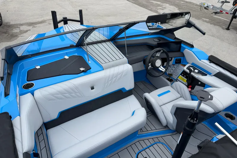  Yacht Photos Pics 2026 Nautique Ski Nautique boat interior with blue and white seating, modern dashboard, and steering wheel.