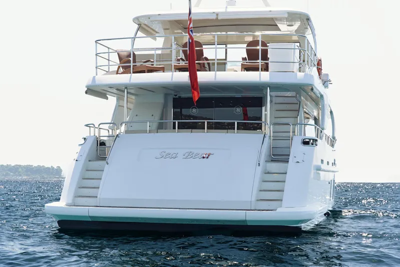 Sea Bear Yacht Photos Pics Luxury yacht Benetti 93 Delfino 2013 on open water, rear view with flag.