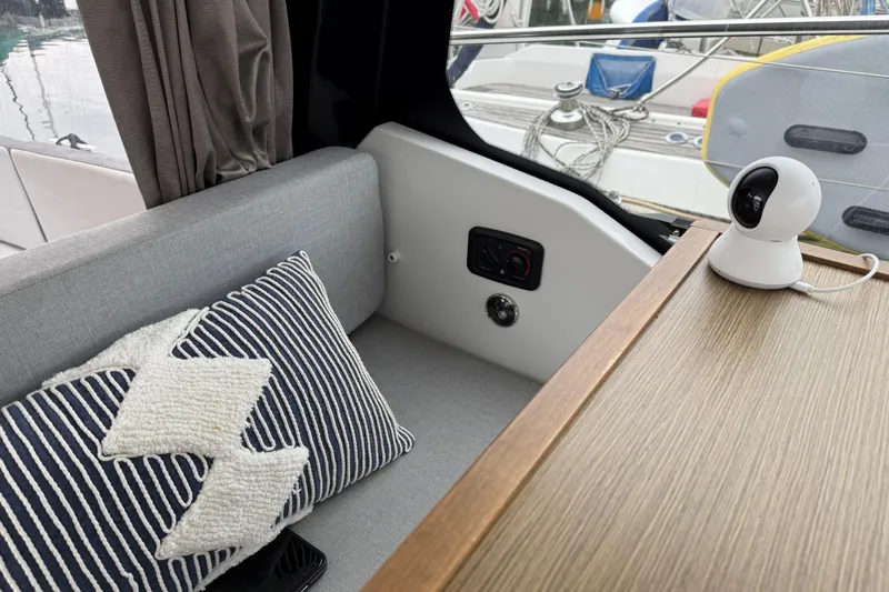  Yacht Photos Pics Interior of 2020 Jeanneau NC 895 with cushion, camera, and wooden table.