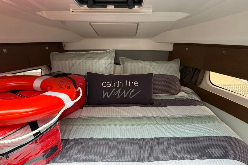  Yacht Photos Pics Cozy cabin interior of 2020 Jeanneau NC 895 with striped bedding and safety equipment.