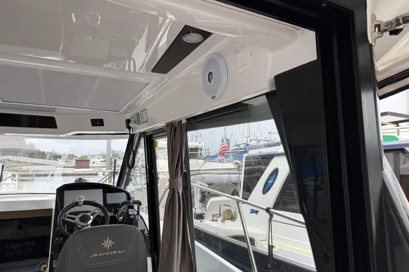  Yacht Photos Pics Interior view of 2020 Jeanneau NC 895 boat cockpit with steering wheel and marina background.