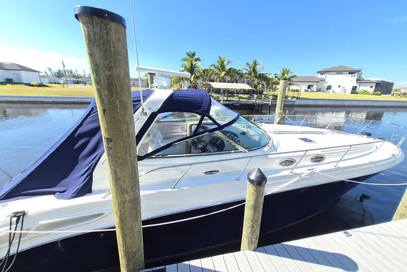  Yacht Photos Pics 2004 Sea Ray 380 Sundancer yacht docked by waterfront homes under clear blue sky.