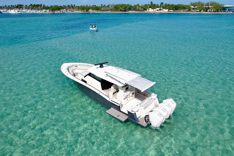  Yacht Photos Pics 2021 Scout 420 LXF boat on clear turquoise water, near a tropical shoreline.