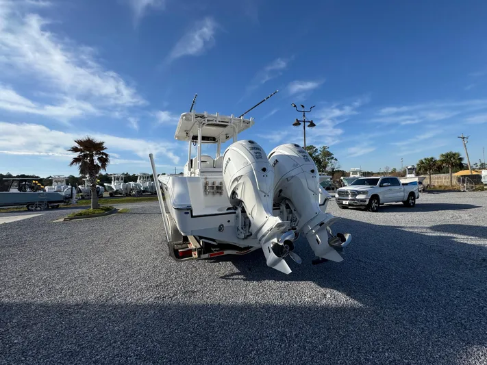  Yacht Photos Pics 2017 Edgewater 320CC boat with dual outboard motors in a gravel lot under blue sky.