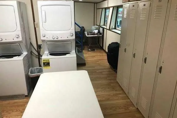 Southern Comfort Yacht Photos Pics Laundry room with stacked washers, dryers, lockers, and folding table on wooden floor.
