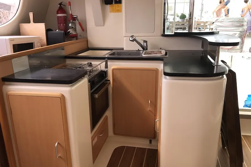  Yacht Photos Pics Compact kitchen in a 2006 Leopard 40 catamaran with modern appliances and wooden cabinetry.