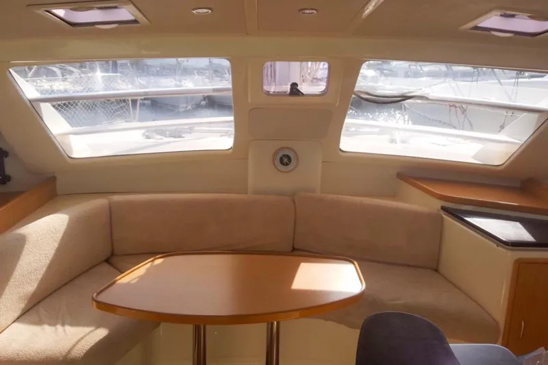  Yacht Photos Pics Interior of 2006 Leopard 40 catamaran with beige seating and wooden table.