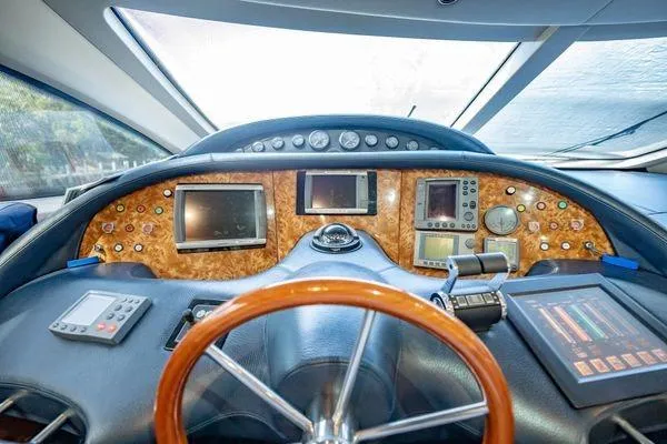 The Cure Yacht Photos Pics Cockpit of 2003 Azimut 80 Carat yacht with advanced navigation instruments and wooden steering wheel.
